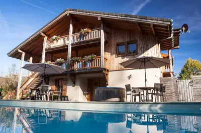 a log house with a pool in front of it at La Terrasse - 3 bedrooms with private Hot Tub in Samoëns