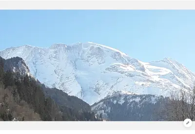 a snow covered mountain in the distance with trees at Casa Mia in Saint-Gervais-les-Bains