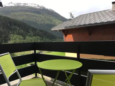 a green table and chairs on a balcony with a mountain at Les Esserts in Les Houches