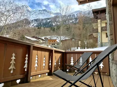 a pair of deck chairs on a balcony with snow covered mountains at Kandahar in Les Houches
