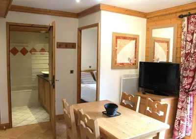 a living room with a table and a television at Reine des Prés in Samoëns