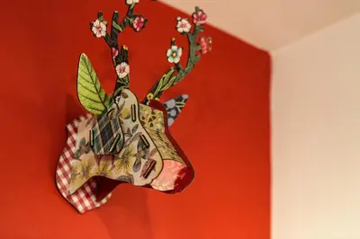 a figurine of a deer head hanging on a red wall at Biolay 1 in Chamonix-Mont-Blanc