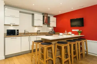 a kitchen with white cabinets and a red wall at Biolay 1 in Chamonix-Mont-Blanc