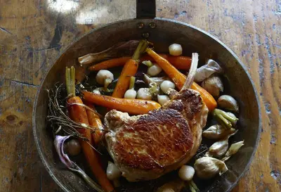 a pan filled with meat and vegetables on a table at Chalet des Fermes de Marie, avec services, Collection Chalets des Fermes in Megève