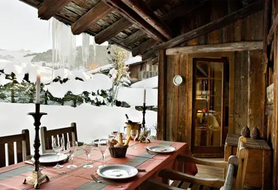 a wooden table with plates and wine glasses on it at Chalet des Fermes de Marie, avec services, Collection Chalets des Fermes in Megève