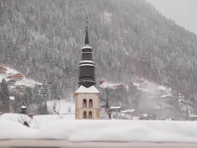 a church with a steeple in the snow at Le Grand Panorama 5 Étage Balcon Vue sur La Montagne in Saint-Gervais-les-Bains