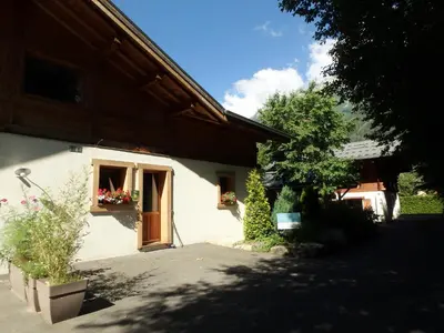 a white house with a window and flowers in a yard at Le Chalet de l'Ours Blanc in Chamonix-Mont-Blanc
