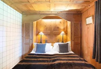 a bedroom with a large bed with wooden walls at Chalet Chatel, avec services, Collection Chalets des Fermes - Megève in Megève