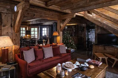 a living room with a red couch and a christmas tree at Chalet Chatel, avec services, Collection Chalets des Fermes - Megève in Megève