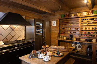 a kitchen with a stove and a counter with food on it at Chalet Chatel, avec services, Collection Chalets des Fermes - Megève in Megève