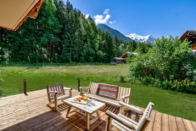 two chairs and a table on a wooden deck at Chalet Sanaz in Chamonix-Mont-Blanc