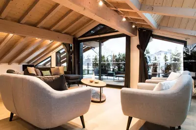 a living room with couches and chairs and windows at Chalet Belachat in Chamonix-Mont-Blanc