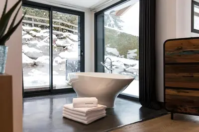 a bathroom with a white bath tub in front of a window at Chalet Belachat in Chamonix-Mont-Blanc