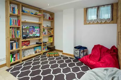 a living room with a red couch and book shelves at Chalet des Souchettes - Chamonix All Year in Chamonix-Mont-Blanc