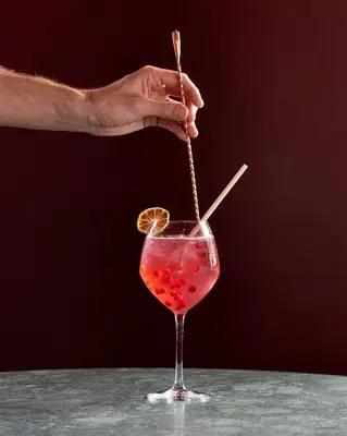 a person is stirring a drink with a stick at Hôtel Restaurant la Couronne in Chamonix-Mont-Blanc