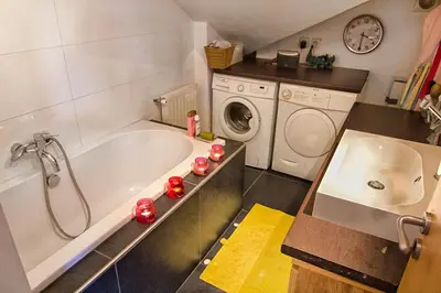 a bathroom with a tub and a washing machine at Le Mont Fleuri Saint Gervais Les Bains in Saint-Gervais-les-Bains