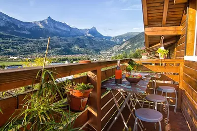 a balcony with a table and chairs and mountains at Le Mont Fleuri Saint Gervais Les Bains in Saint-Gervais-les-Bains
