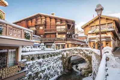 a bridge over a river in front of a building at Mamie Megève in Megève