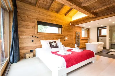a bedroom with a white bed and a wooden wall at Chalet Rass in Chamonix-Mont-Blanc