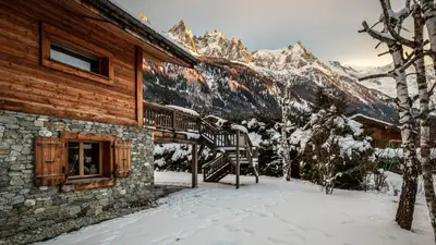 a large wooden house with mountains in the background at Chalet Rass in Chamonix-Mont-Blanc