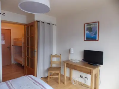 a bedroom with a bed and a desk with a television at Edelweiss in Samoëns