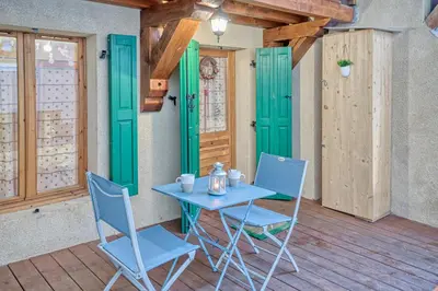 a table and chairs on a porch with green doors at Studio 