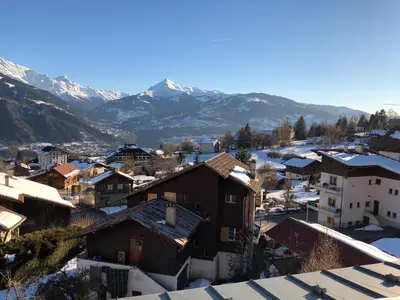 a small town with snow covered mountains in the background at Meridies in Plateau dʼAssy