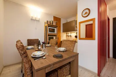 a dining room table with chairs and a clock on the wall at Chamonix Sud - Marguerite B215 - Happy Rentals in Chamonix-Mont-Blanc