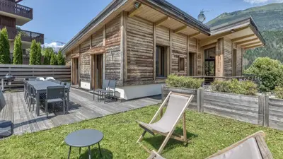 a wooden house with a deck with a table and chairs at Chalet Base Camp in Les Houches