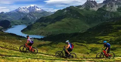 three people riding bikes on a hill with a view of mountains at Apartment Marcel - Cosy Chamonix Haven Mont Blanc in Chamonix-Mont-Blanc