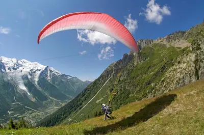a person flying a parachute on a mountain at Apartment Marcel - Cosy Chamonix Haven Mont Blanc in Chamonix-Mont-Blanc