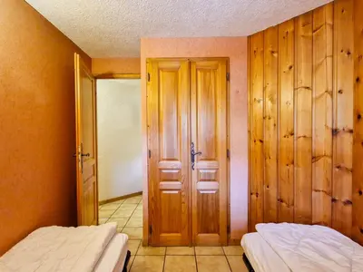 two beds in a room with wooden walls and a door at Appartement spacieux au centre station avec balcon, 3 pièces pour 8 personnes - FR-1-425-2 in Flaine