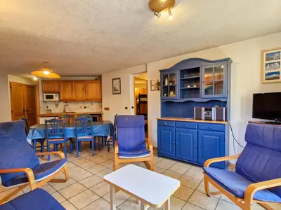 a living room with blue chairs and a kitchen at Appartement spacieux au centre station avec balcon, 3 pièces pour 8 personnes - FR-1-425-2 in Flaine