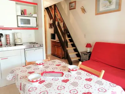 a small kitchen with a table and a red couch at Morillon 1100: 3 pièces cosy pour 5 pers., balcon sud, à 150m des pistes - FR-1-815-60 in Morillon