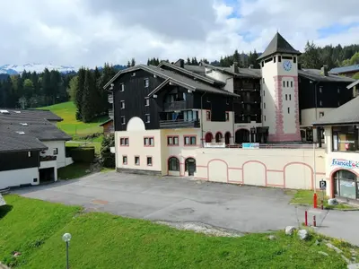 a hotel in the snow with cars parked in a parking lot at Morillon 1100: 3 pièces cosy pour 5 pers., balcon sud, à 150m des pistes - FR-1-815-60 in Morillon