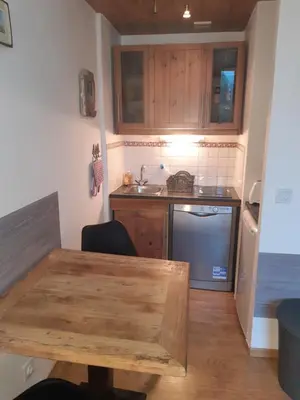 a small kitchen with a wooden table and a sink at Le Carlton in Chamonix-Mont-Blanc