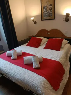 a bedroom with a large bed with red and white pillows at Le Carlton in Chamonix-Mont-Blanc