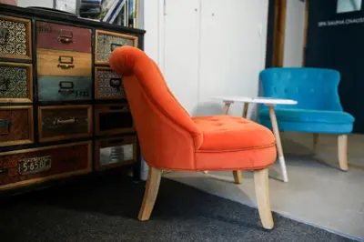 an orange chair and a blue chair next to a cabinet at Appart'Hotel Aiguille Verte & Spa in Chamonix-Mont-Blanc