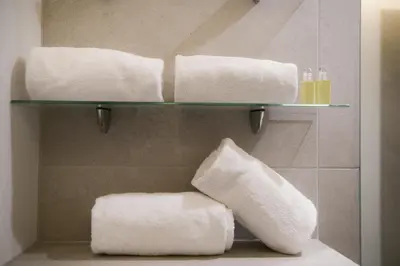 a bathroom with three towels on a shelf at Appart'Hotel Aiguille Verte & Spa in Chamonix-Mont-Blanc