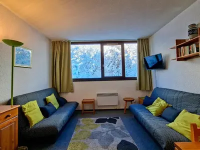 a living room with a blue couch and yellow pillows at Studio spacieux pour 4 personnes, proche des pistes - FR-1-425-74 in Flaine