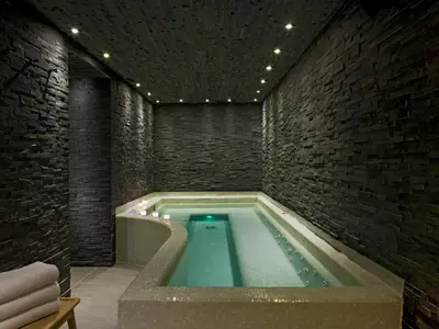 a swimming pool in a room with a brick wall at Le Faucigny - Hotel de Charme & SPA in Chamonix-Mont-Blanc