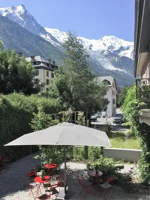 a white umbrella and chairs with mountains in the background at Le Faucigny - Hotel de Charme & SPA in Chamonix-Mont-Blanc