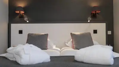 a white couch in a room with two pillows at Le Faucigny - Hotel de Charme & SPA in Chamonix-Mont-Blanc
