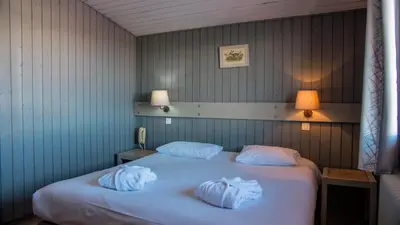 a bedroom with a bed and a window and a chair at Hôtel Arbois Bettex in Saint-Gervais-les-Bains