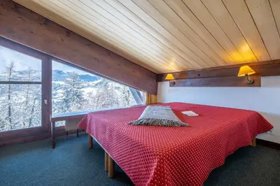 a bedroom with a red bed in a room with a window at Résidence Pierre & Vacances Le Mont d'Arbois in Megève