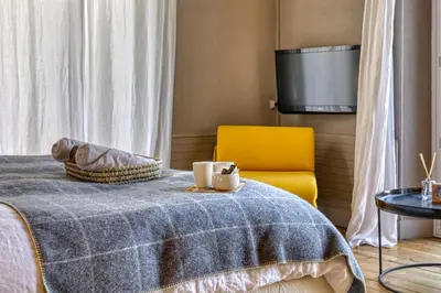 a bed with a blue blanket and a yellow chair at La Féline Blanche Adult Only in Saint-Gervais-les-Bains