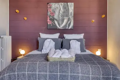 a bed with a basket of towels on it at La Féline Blanche Adult Only in Saint-Gervais-les-Bains