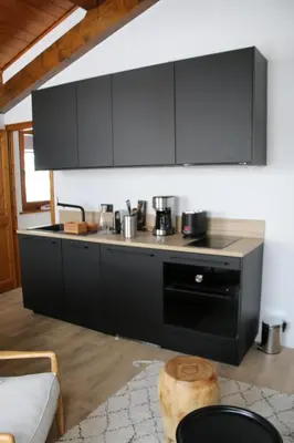 a kitchen with black cabinets and a stove at La Résidence de L'Ours in Megève