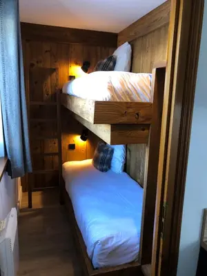 two bunk beds in a room with wooden walls at La Résidence de L'Ours in Megève