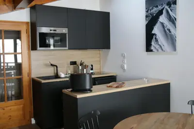 a kitchen with black cabinets and a wooden table at La Résidence de L'Ours in Megève